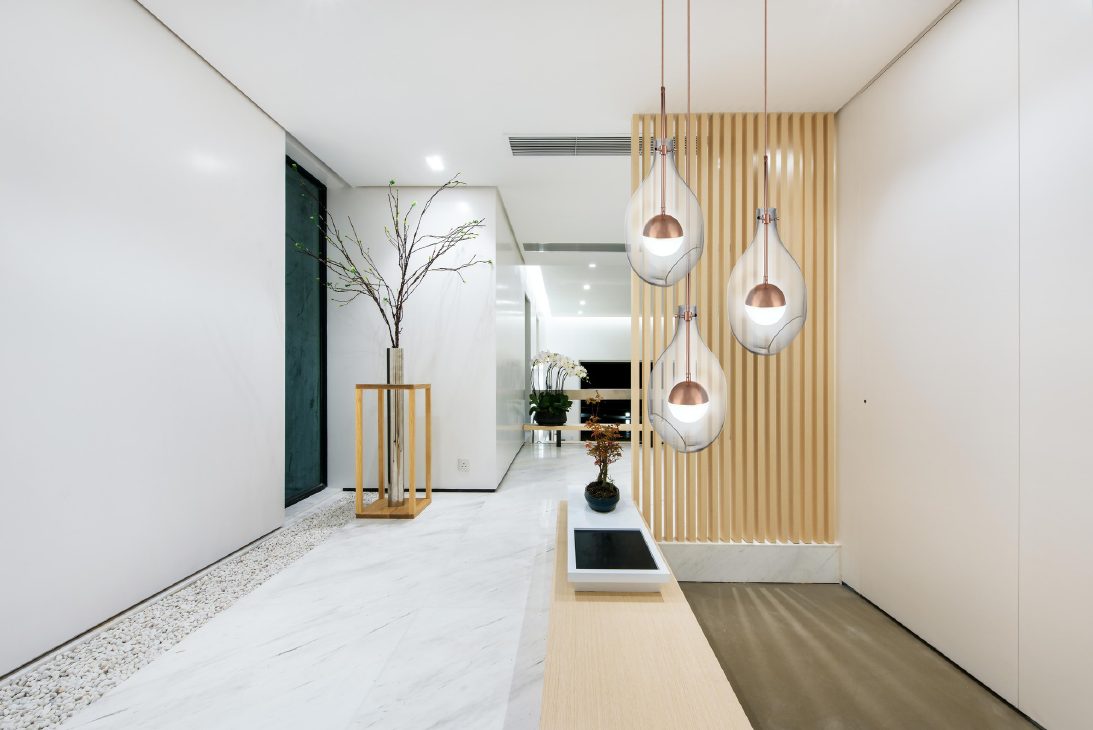 Clear glass and steel pendant lamps with brushed rose gold detailing in a hallway